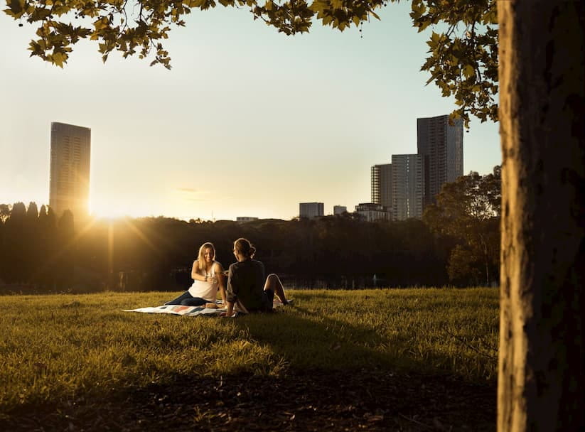 A couple sitting on a picnic rug at Sydney's Bicentennial Park at sunset
